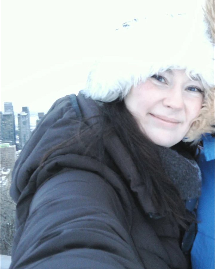 Shelby Mason bundled up in a winter coat, with a city skyline behind her
